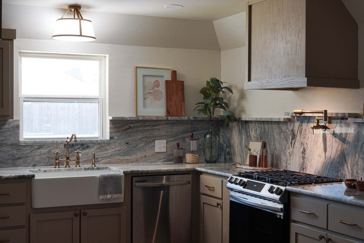 A kitchen with marble backsplash and brass fixtures