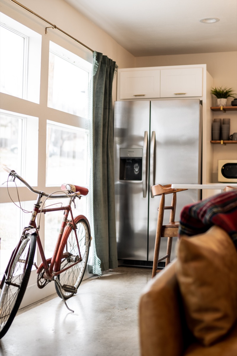 A red bicycle by tall windows in a loft kitchen